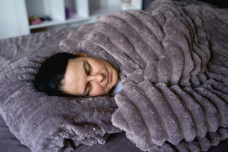 person sleeping under a weighted blanketの写真素材