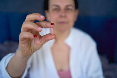 Person in white robe holding a supplement or medicationの写真素材