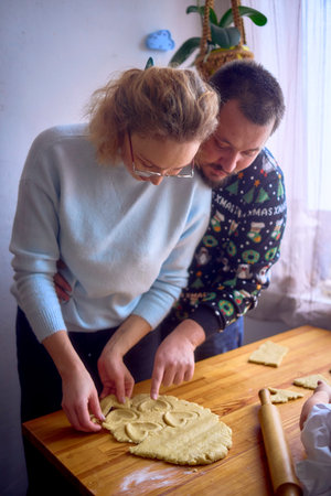 husband and wife are cooking Christmas cookies in the kitchen