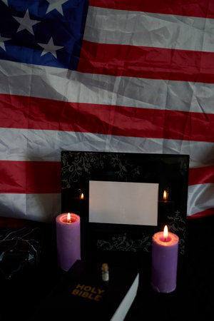 funeral of an American hero, photo frame, candles, marble urn for ashes, holy bible and spiritual bracelet with black crossの写真素材