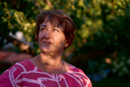 Portrait of a happy senior woman in a pink dress during sunset golden hour