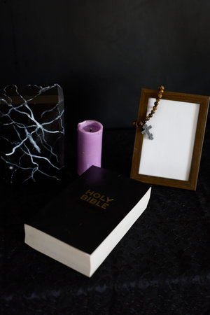 funeral, photo frame, candles, marble urn for ashes, holy bible and spiritual bracelet with black crossの写真素材