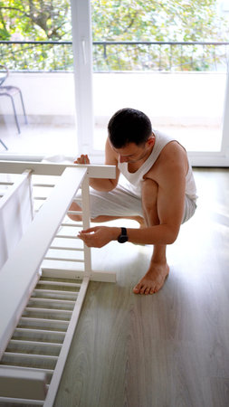 New dad to be building a cradle for his newborn in a bright simple room