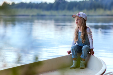 cute girl preschooler summer evenings resting on the lakeの写真素材