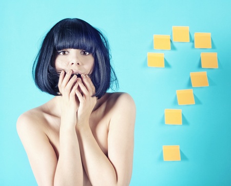 portrait of a beautiful young woman posing in studio with  question mark signの写真素材
