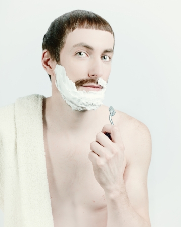 young man shaving with towel on the shoulders. の写真素材