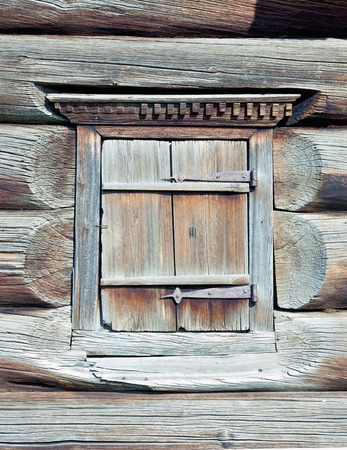 A small closed window in the wall of an old wooden house の写真素材