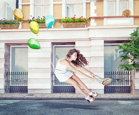Balloons fly with young beautiful girl. Creative conceptの写真素材