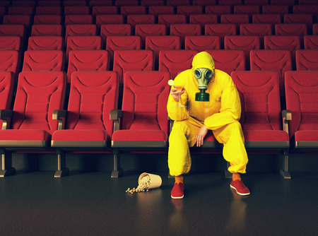 the man in a protective coverall  sitting in an empty theater. Creative conceptの写真素材