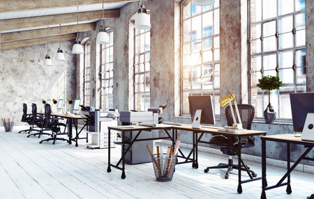 A sunlit, modern office interior with an industrial loft design, featuring concrete walls, large windows, and whitewashed wood floors. The empty workspace includes.の写真素材