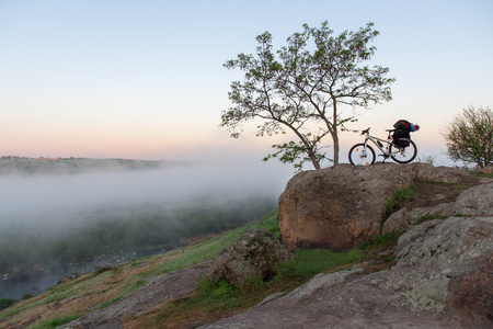 Bicycle over misty canyon, river and stonesの写真素材
