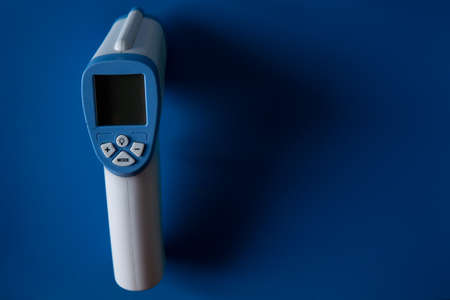 Digital thermo gun on blue backgroundの写真素材