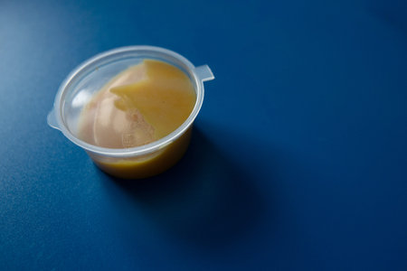 melt cheese sauce on plastic cup with blue backgroundの写真素材
