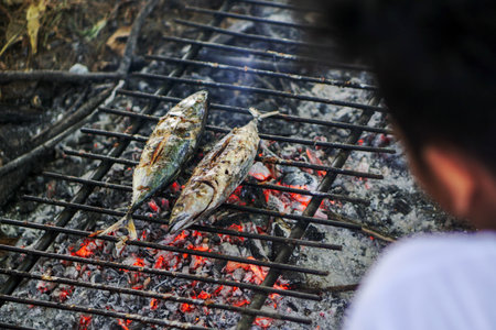 Grilled mackerel fish on the grill with flames and smoke.の写真素材