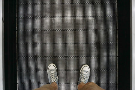 Man's feet walking on escalator, closeup.
