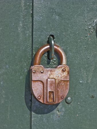 Green steel garage door locked with padlockの写真素材