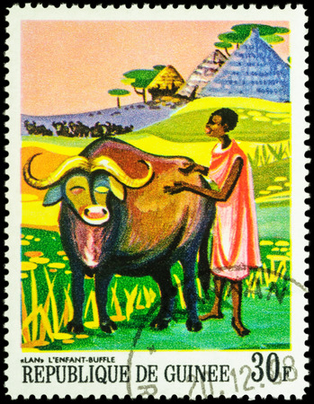 MOSCOW, RUSSIA - MAY 12, 2016: A stamp printed in Guinea shows Lan, african bull and black woman, series "Paintings of African Legends", circa 1968のeditorial素材
