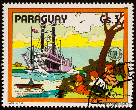 Moscow, Russia - July 30, 2017: A stamp printed in Paraguay shows Finn, Friends and Riverboat on Mississippi, Adventures of Tom Sawyer by Mark Twain, series "International Year of Youth", circa 1985のeditorial素材