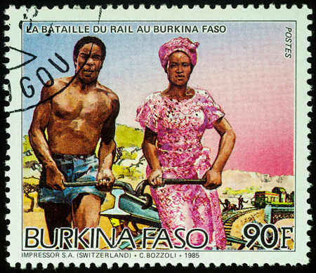 Moscow, Russia - August 07, 2017: A stamp printed in Burkina Faso, shows African man and woman carrying rail, series "Railroad Construction", circa 1986のeditorial素材