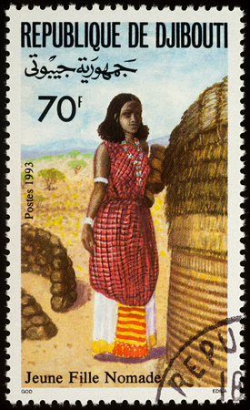 Moscow, Russia - August 06, 2017: A stamp printed in Djibouti, shows young woman in a national African clothes, series "Traditional costumes", circa 1993のeditorial素材