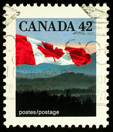 Moscow, Russia - December 29, 2017: A stamp printed in Canada, shows Canadian national flag over hills, circa 1991のeditorial素材