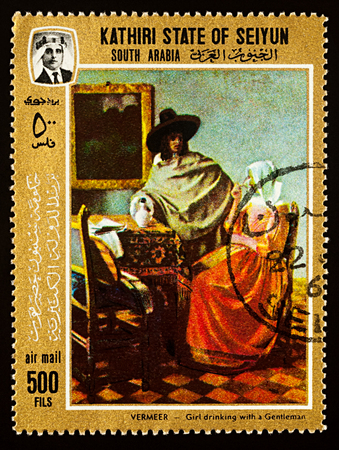 Moscow, Russia - December 31, 2017: A stamp printed in Kathiri State of Seiyun (South Arabia), shows painting "Girl drinking with a Gentleman" by Dutch painter Jan Vermeer (1632-1675), circa 1967のeditorial素材