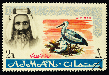 Moscow, Russia - February 05, 2018: A stamp printed in Ajman shows Sheik Rashid and White Stork (Ciconia ciconia), series "Native fauna", circa 1965のeditorial素材