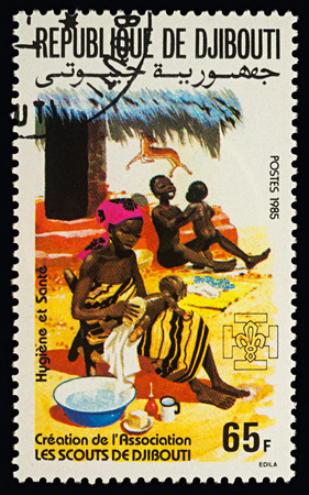 Moscow, Russia - February 22, 2018: A stamp printed in Djibouti shows young African woman washing baby, hygiene and family health care, series "Scouting", circa 1985のeditorial素材
