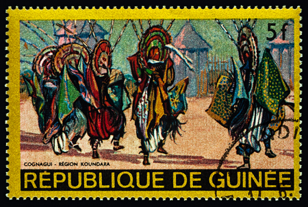 Moscow, Russia - February 27, 2018: A stamp printed in Guinea shows traditional dance in African village, Cognagui - Koundara Region, series "Regional Costumes and Habitations", circa 1968のeditorial素材