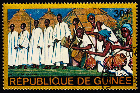 Moscow, Russia - February 28, 2018: A stamp printed in Guinea shows group of musicians with traditional drums in African village, Kankan Region, series "Regional Costumes and Habitations", circa 1968のeditorial素材