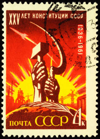 Moscow, Russia - April 18, 2020: stamp printed in USSR (Russia), shows hands with sickle and hammer on rising sun background, dedicated to the 25th Anniversary of Soviet Constitution, circa 1961のeditorial素材