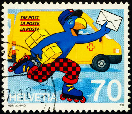 Moscow, Russia - February 01, 2021: stamp printed in Switzerland shows Comic figure Globi as postman, carrying parcel and letter, series 20th International Comics Festival, Sierre, circa 1997のeditorial素材