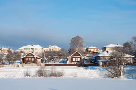 Suburban winter landscape, country houses on the banks of frozen lake, sunny winter dayの写真素材