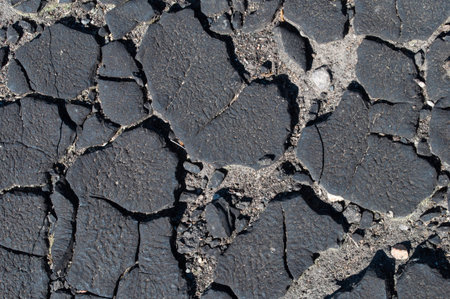 Closeup of old black cracked weathered tar background