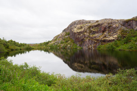 Small lake with a rocky shore in the tundra, cloudy summer day. Rybachy peninsula, Murmansk region, Northern Russiaの写真素材