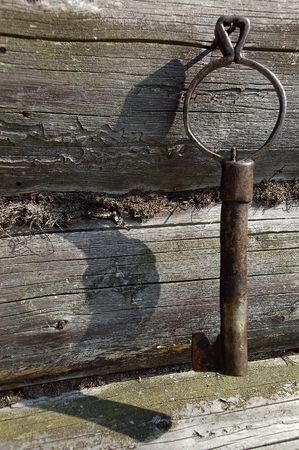 Old forged key on the nail in the wall of the village log-house.の写真素材