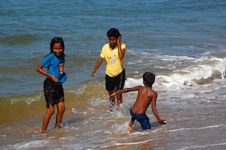 Two sisters and their younger brother are having fun on the beach. The photo was taken in Sri Lanka in December, 2008.のeditorial素材