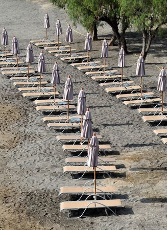 Folded umbrellas on the empty beach on Crete island in Greece.の写真素材