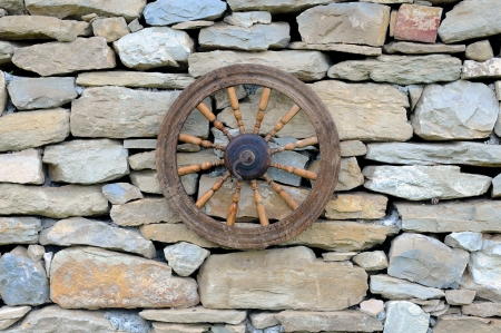 Vintage spinning wheel against stone wall backgroundの写真素材