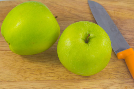 Green apples and knife on chopping blockの写真素材