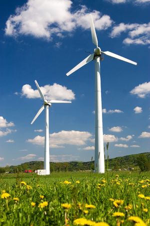 Windmills against blue sky with white clouds and yellow flowers on the groundの写真素材