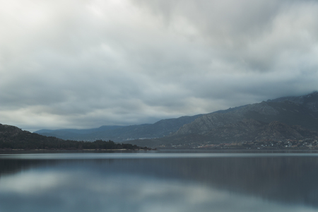 Beautiful reflections of clouds and mountains in the water of a lakeの写真素材