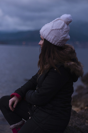 Young girl facing a lake during a cloudy dayの写真素材