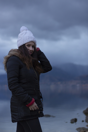 Young girl facing a lake during a cloudy dayの写真素材