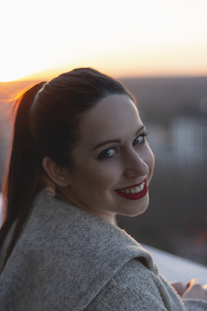 Girl watching the sunset from the top of a roof in the center of the cityの写真素材