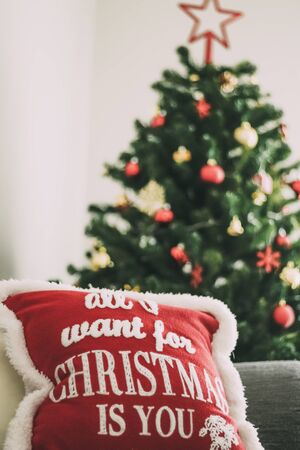 Nice Christmas tree decorated with different colored ornaments next to a cushion with a beautiful and colorful Christmas design - selective focus -の写真素材