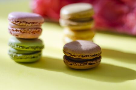 Colorful macaroons on a lime green background, stacked and illuminated by sun raysの写真素材