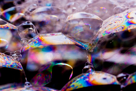 Macro photography of various soap bubbles creating different geometric shapes with striking colors,...