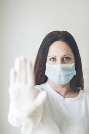 Young brown-haired woman protected with a medical mask and latex gloves, COVID-19, coronavirus, selective focusの写真素材