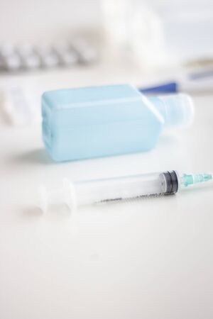 Medical supplies kit for health emergencies, consisting of thermometer, bandages, analgesics, antiseptics, serum, hand sanitizer, needles and syringe, on white background, selective focusの写真素材